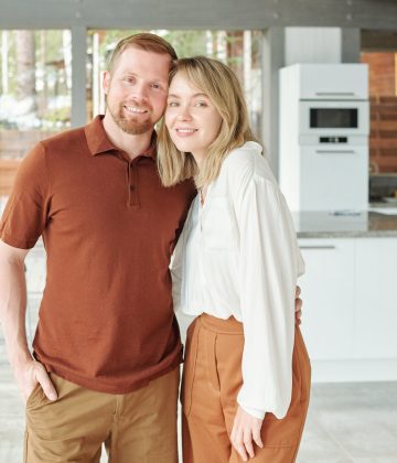 Portrait of happy beautiful couple embracing against modern kitchen in cottage house